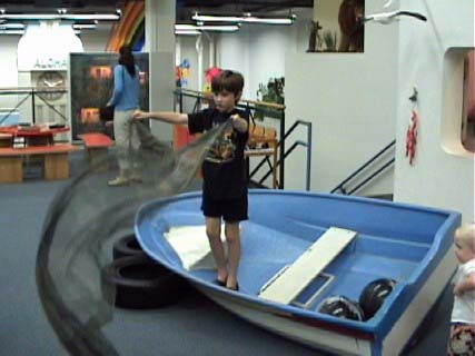 Boy playing fisherman in boat in museum